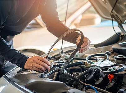 Mécanicien remplaçant une courroie de moteur dans un compartiment moteur de voiture à Brissac Quince dans le Maine-et-Loire 49