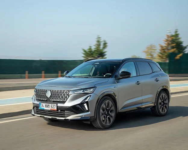 Femme en tenue décontractée appuyée sur une Renault Megane grise devant des montagnes à Brissac Quince dans le Maine-et-Loire 49