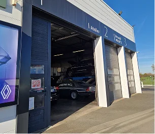 Garage automobile spacieux avec plusieurs voitures en réparation, dont une sur un pont élévateur à Brissac Quince dans le Maine-et-Loire 49