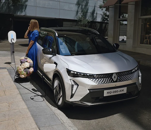 Femme avec fleurs branchant une voiture électrique Renault blanche à Brissac Quince dans le Maine-et-Loire 49